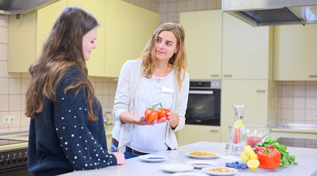 Ernährungsberaterin zeigt Frau Tomaten in der Park Klinik
