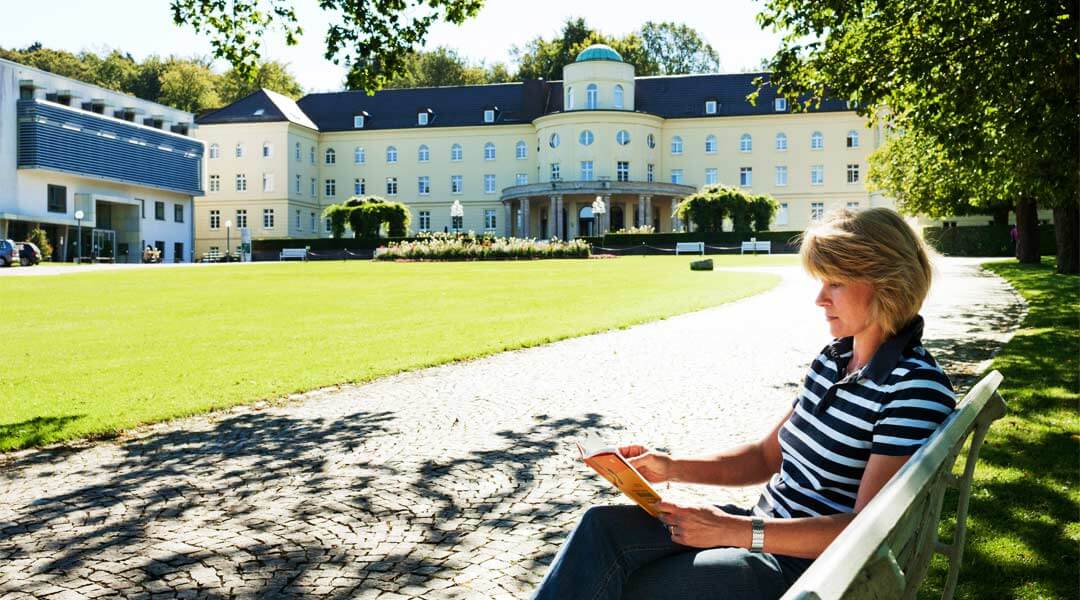 Frau liest vor der Park Klinik ein Buch