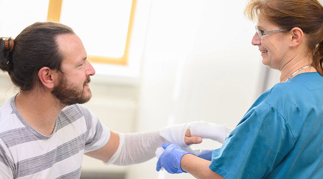 Pflegerin legt einen Verband an die Hand