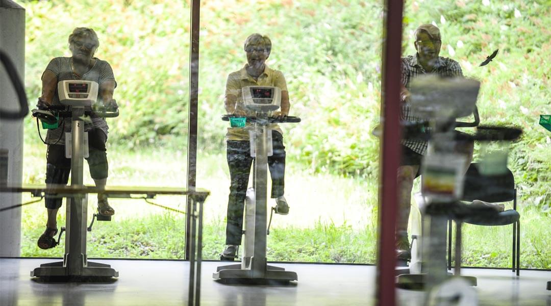 Übungen auf dem Ergometer in der Park Klinik hinter Glassscheibe